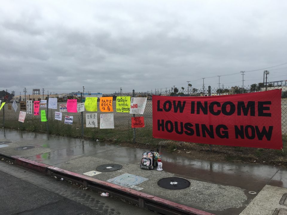 Image depicts protest signs at the site of a proposed development in Los Angeles